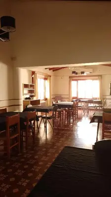 an empty room with tables and chairs and windows at Ribera Sur Hotel - Los Algarrobos - Tanti in Tanti