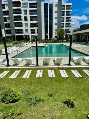 a swimming pool with white chairs and a building at MD Amoblado Córdoba Capital in Cordoba