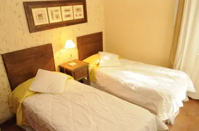 a room with two beds and a table with a lamp at Niderost in Villa Berna