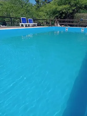 a swimming pool with two blue chairs in it at Loma Dorada Cabañas in Villa General Belgrano