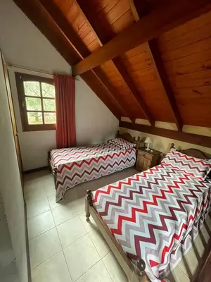 two beds in a room with a wooden ceiling at Loma Dorada Cabañas in Villa General Belgrano