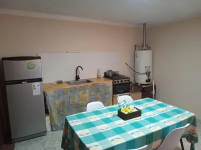 a kitchen with a table and a sink and a refrigerator at Depto Santo Brochero centro in Villa Cura Brochero