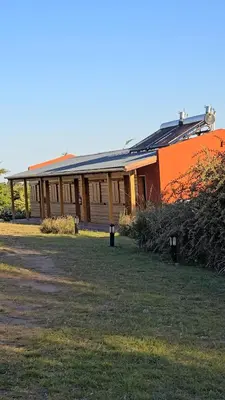 an orange building with a grass field in front of it at El Camino Cabañas y Apart in Villa Berna