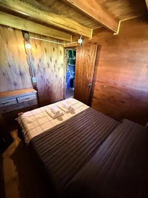 a bedroom with a bed in a wooden room at El Camino Cabañas y Apart in Villa Berna