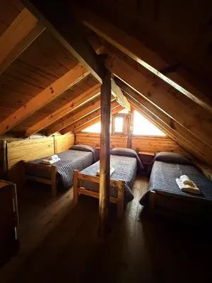 a room with two beds in a wooden attic at El Camino Cabañas y Apart in Villa Berna