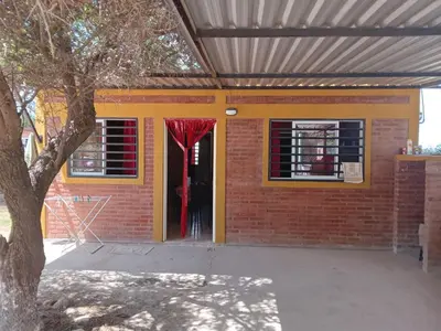 a brick house with a yellow door with a red curtain at Granate in Villa Cura Brochero