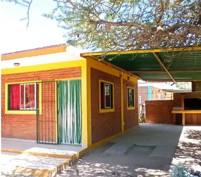 a yellow and red house with a tree at Granate in Villa Cura Brochero