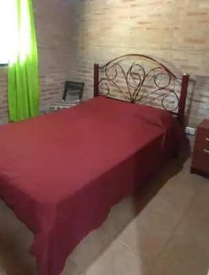 a red bed in a room with a green curtain at Granate in Villa Cura Brochero