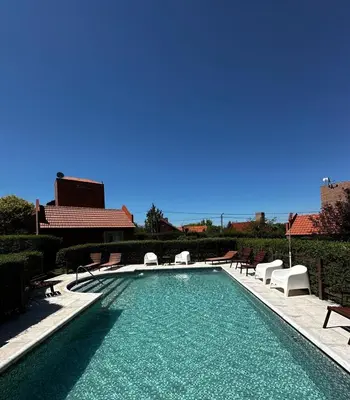 a swimming pool with chaises and chairs in front of a building at Cabañas El Maiten in Merlo
