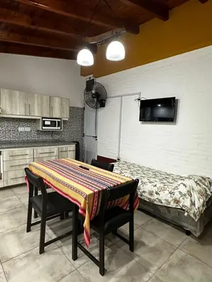 a kitchen with a table and a bed in a room at Cabañas El Maiten in Merlo
