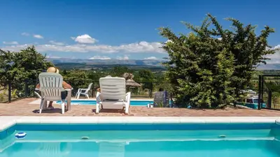a man sitting in lawn chairs next to a swimming pool at Cabañas & Suites Vista Hermosa in Los Reartes