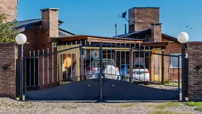 a gate in front of a house with cars in it at Cabañas & Suites Vista Hermosa in Los Reartes