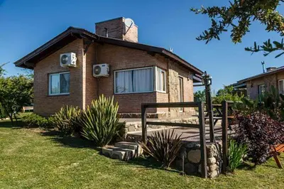 a small brick house with a porch in a yard at Cabañas & Suites Vista Hermosa in Los Reartes