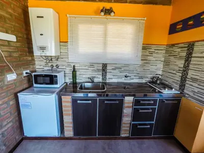 a small kitchen with a sink and a microwave at Cabañas & Suites Vista Hermosa in Los Reartes