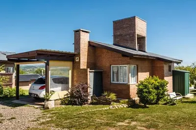 a house with a car parked in front of it at Cabañas & Suites Vista Hermosa in Los Reartes