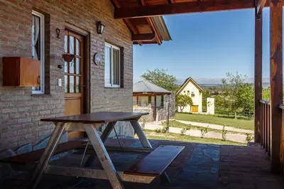 a wooden picnic table in front of a brick building at Cabañas & Suites Vista Hermosa in Los Reartes