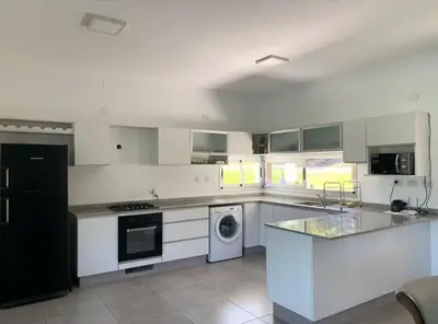 a large kitchen with white cabinets and a dishwasher at Tierra Alta, Comarca Serrana in Cordoba