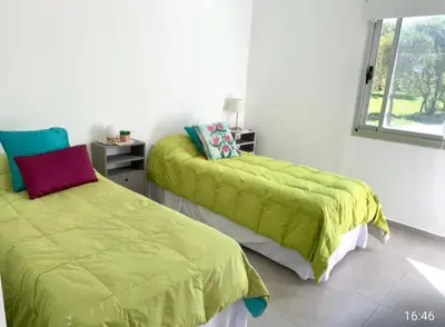 a bedroom with two beds with green sheets and a window at Tierra Alta, Comarca Serrana in Cordoba