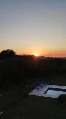 a sunset over a swimming pool with chairs and the sunvisor at Tierra Alta, Comarca Serrana in Cordoba