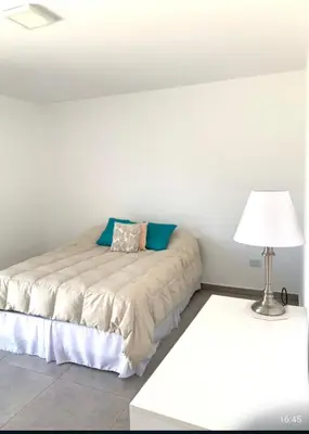 a white bedroom with a bed and a lamp at Tierra Alta, Comarca Serrana in Cordoba