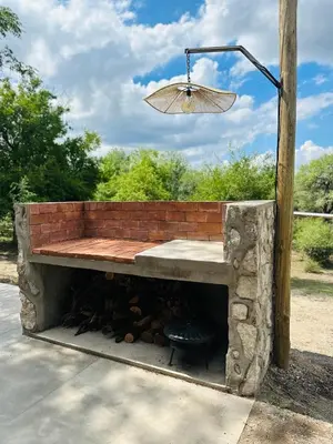 a brick bench with an umbrella and a fire pit at Casa Simona in Las Rabonas