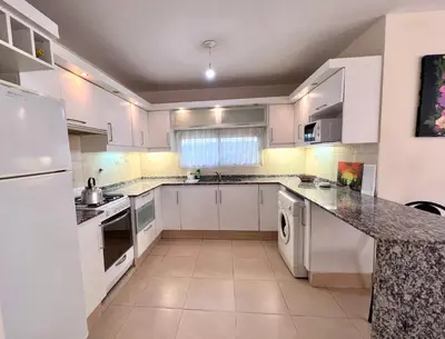 a white kitchen with white cabinets and appliances at Hermosa y amplia casa con pileta in San Antonio de Arredondo