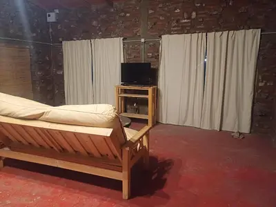 a bedroom with a bed and a tv and curtains at La Casa de Piedra in Villa Santa Cruz del Lago