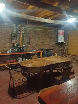 a kitchen with a table and chairs in a room at La Casa de Piedra in Villa Santa Cruz del Lago