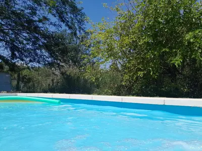 a blue swimming pool with trees in the background at rafaella in Villa Anizacate