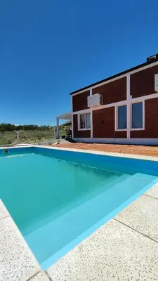 a house with a swimming pool in front of a building at Cabañas Estancia del Pilar - Cabañas de montaña in Estancia Vieja
