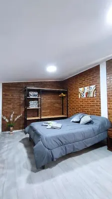 a large bed in a bedroom with a brick wall at Cabañas Estancia del Pilar - Cabañas de montaña in Estancia Vieja