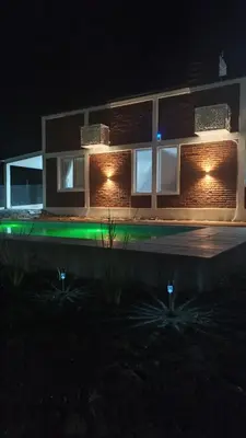 a building with lights on the side of it at night at Cabañas Estancia del Pilar - Cabañas de montaña in Estancia Vieja