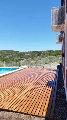a wooden deck next to a swimming pool at Cabañas Estancia del Pilar - Cabañas de montaña in Estancia Vieja