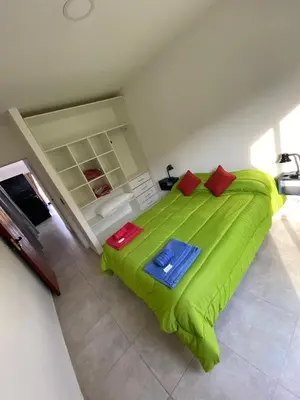a bedroom with a green bed with red pillows at Complejo Giraluna in Almafuerte