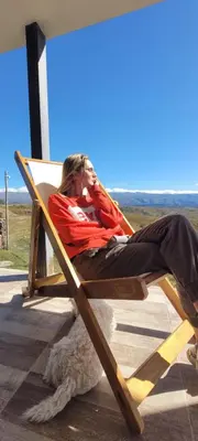a man sitting in a chair with a dog at Mirada al Champaqui - Departamento de Montaña in Villa Yacanto