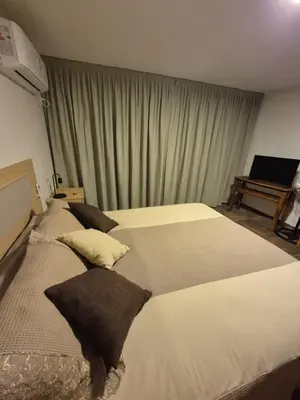 a bedroom with two beds with pillows and a piano at Mirada al Champaqui - Departamento de Montaña in Villa Yacanto
