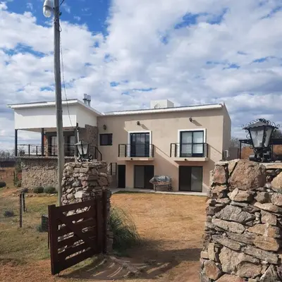 a house with a fence in front of it at Mirada al Champaqui - Departamento de Montaña in Villa Yacanto