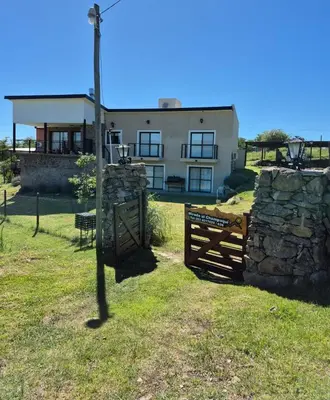 a house with a fence and a stone wall at Mirada al Champaqui - Departamento de Montaña in Villa Yacanto