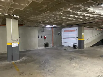 a garage with a white garage door in a parking lot at Edificio Veneto IV - Departamento centrico frente al puente peatonal in Villa Carlos Paz