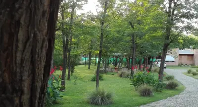 a park with trees and flowers in the grass at Alma Serrana Apart Cabañas - Solo Adultos in Nono
