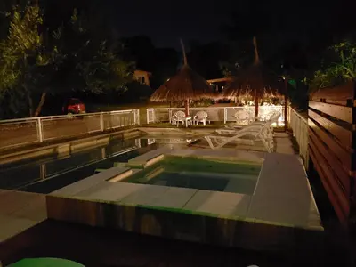 a swimming pool at night with a table and chairs at Alma Serrana Apart Cabañas - Solo Adultos in Nono