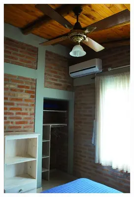 a bedroom with a ceiling fan and a brick wall at Alma Serrana Apart Cabañas - Solo Adultos in Nono