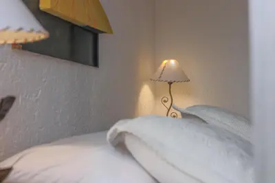 a bedroom with a bed with white sheets and a lamp at Cabañas La Ernestina in Villa Carlos Paz