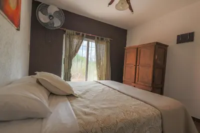 a bedroom with a bed with a window and a fan at Cabañas La Ernestina in Villa Carlos Paz