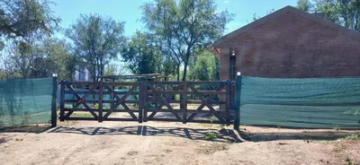 a gate in front of a red barn at Cabaña Claro de Luna in Merlo