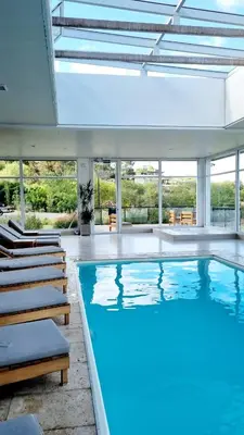 a large swimming pool with chairs and a large window at Departamento frente a lago Carlos Paz - Villa Siquiman - Complejo Veneto Village in Villa Parque Siquiman