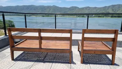 two wooden benches sitting on a balcony overlooking a river at Departamento frente a lago Carlos Paz - Villa Siquiman - Complejo Veneto Village in Villa Parque Siquiman
