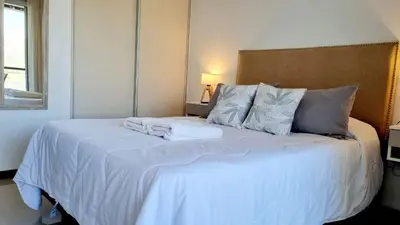a bedroom with a bed with white sheets and pillows at Departamento frente a lago Carlos Paz - Villa Siquiman - Complejo Veneto Village in Villa Parque Siquiman