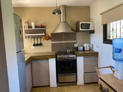 a kitchen with a stove and a microwave at LA CASITA in Villa Carlos Paz