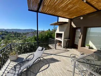 a balcony with chairs and a fireplace on a house at LA CASITA in Villa Carlos Paz